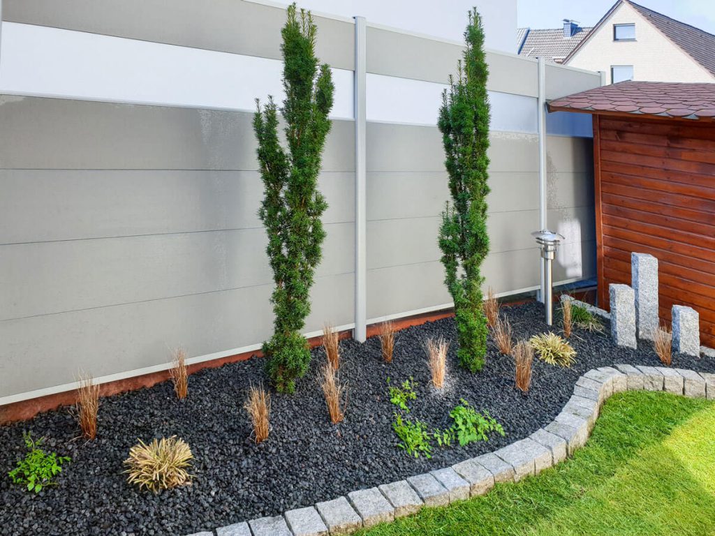 Moderner Sichtschutzzaun mit bepflanztem Granitbeet
